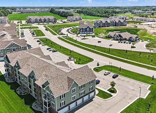 A large, multi-story apartment building with a parking lot in front at Meadowbrooke Apartment Homes in Grand Rapids, MI 49512