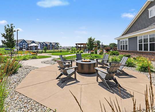 A patio with a fire pit and chairs is surrounded by a grassy lawn at Meadowbrooke Apartment Homes in Grand Rapids, MI 49512
