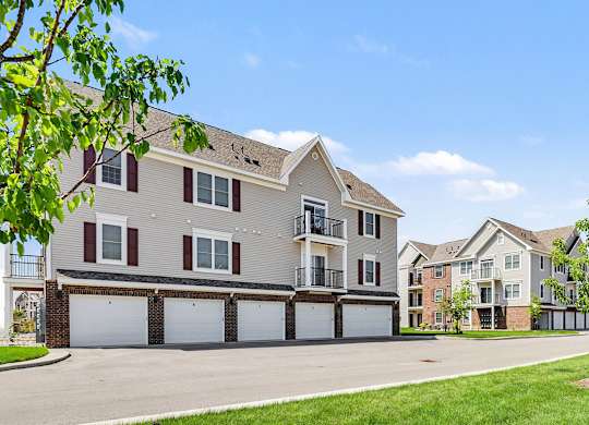 A large apartment building with garages underneath and balconies at Meadowbrooke Apartment Homes in Grand Rapids, MI 49512