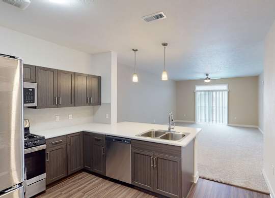 A kitchen overlooking a living room at Meadowbrooke Apartment Homes in Kentwood, MI 49512