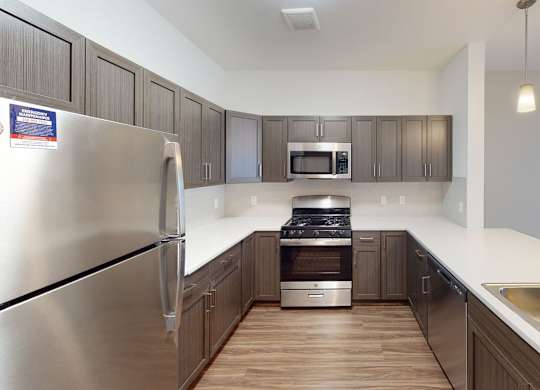 A modern kitchen with stainless steel appliances and a breakfast bar at Meadowbrooke Apartment Homes in Kentwood, MI 49512