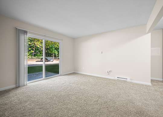 A room with a carpeted floor and a sliding glass door leading to a patiok at Timberlane Apartments, Peoria, Illinois