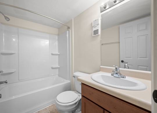 A white bathroom with a toilet, sink, and bathtubk at Timberlane Apartments, Peoria, Illinois