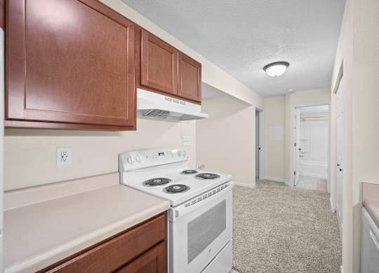 A kitchen with a white stove top oven and wooden cabinetsk at Timberlane Apartments, Peoria, Illinois