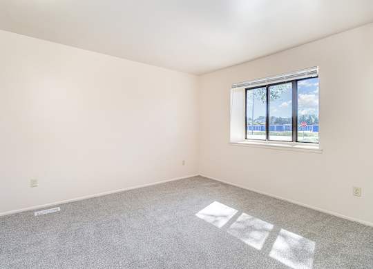 A bedroom with a large window and a carpeted floor at Mount Royal Townhomes, Michigan