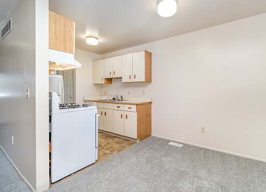 A dining room and kitchen with white appliances and wooden cabinets at Mount Royal Townhomes, Michigan