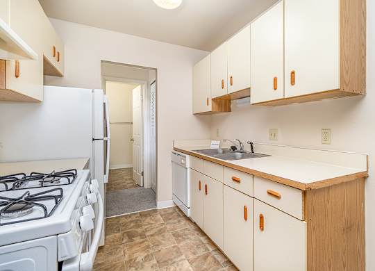 A galley style kitchen with a white gas stove and dishwasher at Mount Royal Townhomes, Michigan