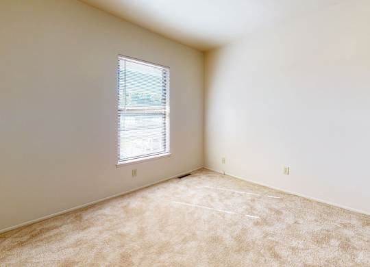 A bedroom with a window and carpeted floor at Mount Royal Townhomes, Kalamazoo, MI