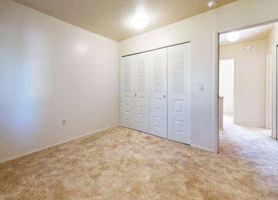 A bedroom with a carpeted floor and a closet at Mount Royal Townhomes, Kalamazoo, MI