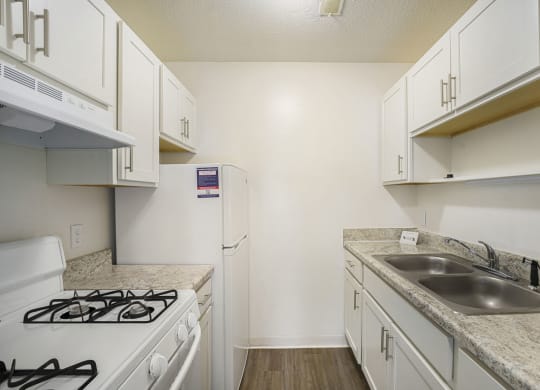 a kitchen with white cabinets and appliances at Newport Village Apartments, Portage, MI