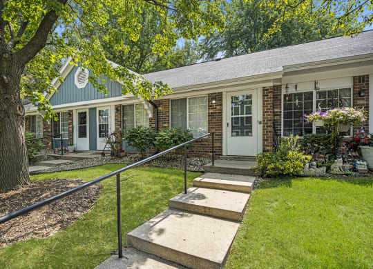 a house with stairs and a tree in front of it at Newport Village Apartments, Portage, MI