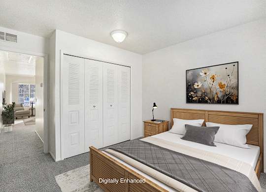 A bedroom with a bed, closet, and plush carpeting at Newport Village Apartments, Portage, MI