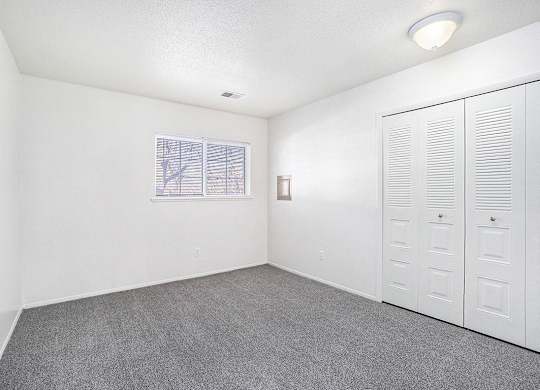 A bedroom with a window and a large closet at Newport Village Apartments, Portage, MI