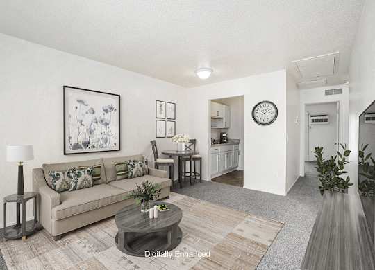 A living room with a couch, coffee table, and a painting on the wall at Newport Village Apartments, Portage, MI