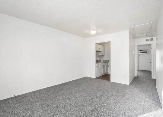 A living and dining room with plush carpeting at Newport Village Apartments, Portage, MI