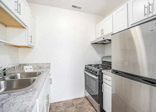 An upgraded kitchen with a stainless steel refrigerator and gas stove at Newport Village Apartments, Portage, MI