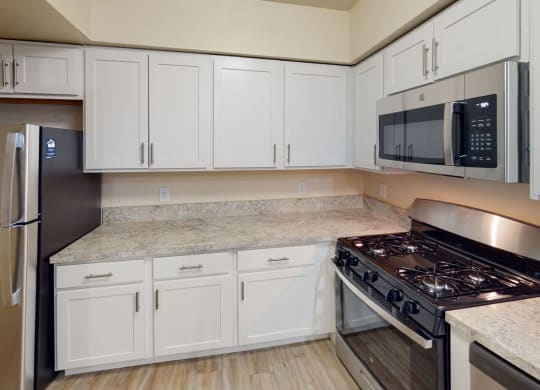 Renovated kitchen with white cabinets and a stove and a microwave at North Pointe Apartments in Elkhart, IN