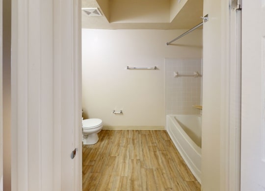 a renovated white bathroom with a toilet and a tub at North Pointe Apartments in Elkhart, IN