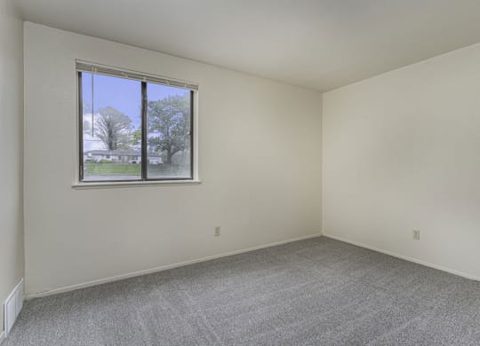Large bedoom with a window and carpeting at Normandy Village Apartments, Michigan City, IN