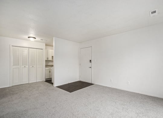 an empty living room and kitchen with white walls and carpet at Normandy Village Apartments, Indiana