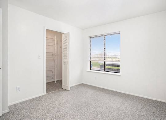 A bedroom with a large window and a door to a walk-in closet at North Pointe Apartments in Elkhart, IN