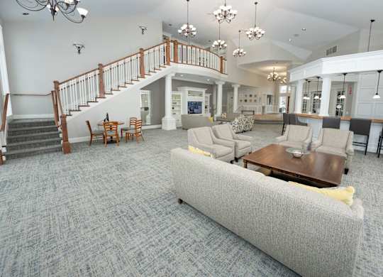 A living room with a grey couch and a staircase  at Northport Apartments, Macomb, MI, 48044
