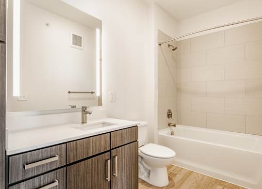 A white toilet sits next to a white sink in a bathroom at Nuvo Flats, Indiana, 46410