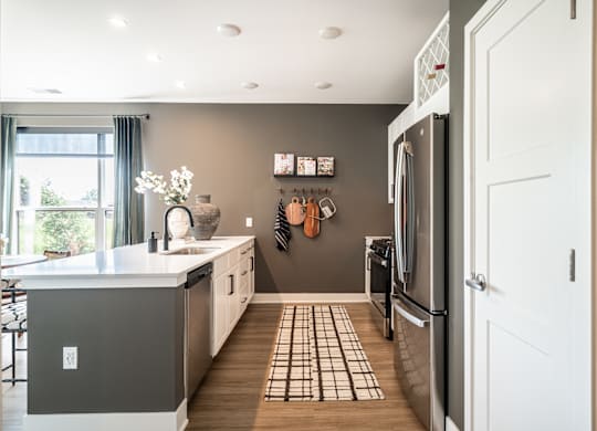 A kitchen with a refrigerator, sink, and a window.