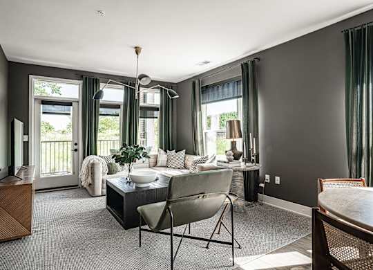 A modern living room with a dark grey wall and a large window with green curtains.