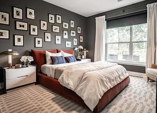 A bedroom with a large bed and a wall of picture frames.