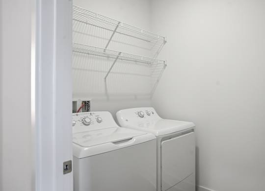 A white washing machine and dryer in a small laundry room at Nuvo Flats, Indiana, 46410