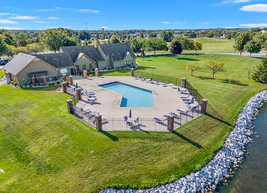 An office and community building with a pool in the back at Oak Shores Apartments in Oak Creek, WI