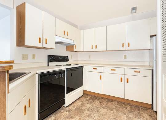 A kitchen with a black stove and dishwasher at Oak Shores Apartments in Oak Creek, WI