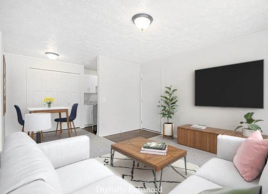 A modern living room with a white couch, a wooden coffee table, and a TV at Old Farm Apartments, Elkhart, Indiana