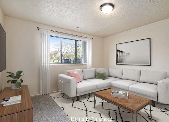 A living room with a white couch, a coffee table, and a large window at Old Farm Apartments, Elkhart, Indiana