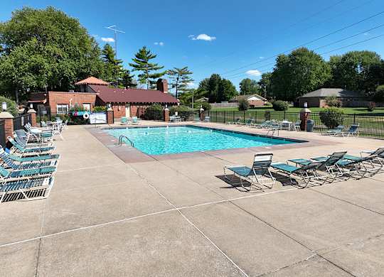 A pool surrounded by chairs and a building in the background at Old Monterey Apartments, Springfield, MO