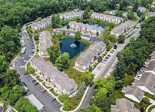 A bird's eye view of apartment community with buildings, a swimming pool, and a pond at Orchard Lakes Apartments, Toledo, 43615