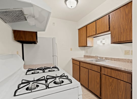 a kitchen with a white stove top oven next to a sink and a refrigerator at Beacon Hill and Great Oaks Apartments, Rockford