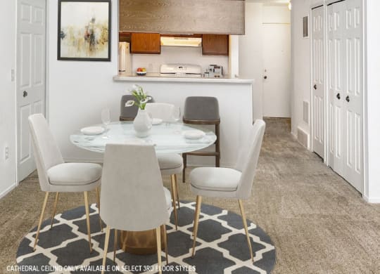 a dining area with a white table and chairs and a kitchen in the background  at Northport Apartments, Macomb, MI, 48044