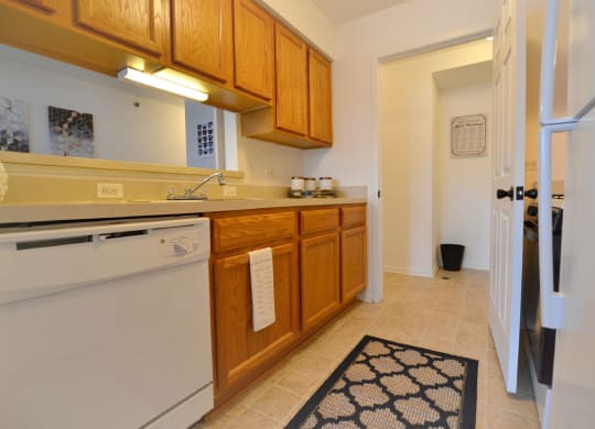 a kitchen with wooden cabinets and a white dishwasher  at Northport Apartments, Michigan