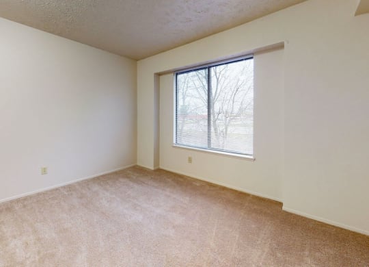 a bedroom with a large window and carpeting