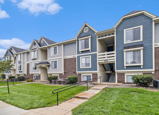 Exterior of apartment building with shade trees and landscaped grounds at Pine Knoll Apartments, Battle Creek
