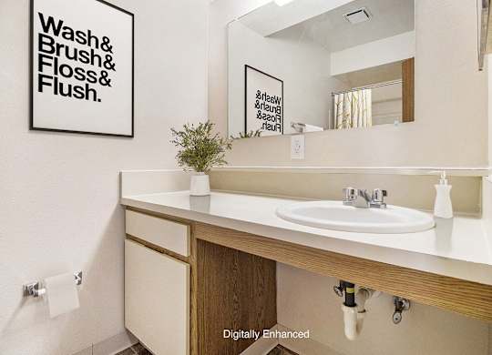 A bathroom with a sink and large mirror at Pine Knoll Apartments, Battle Creek