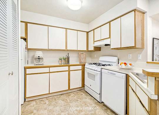 A kitchen with white appliances and wooden cabinets at Pine Knoll Apartments, Battle Creek