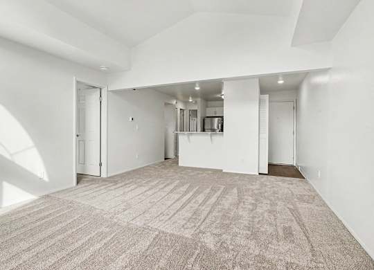 A large, empty dining room with a carpeted floor and white walls at Pine Knoll Apartments, Battle Creek