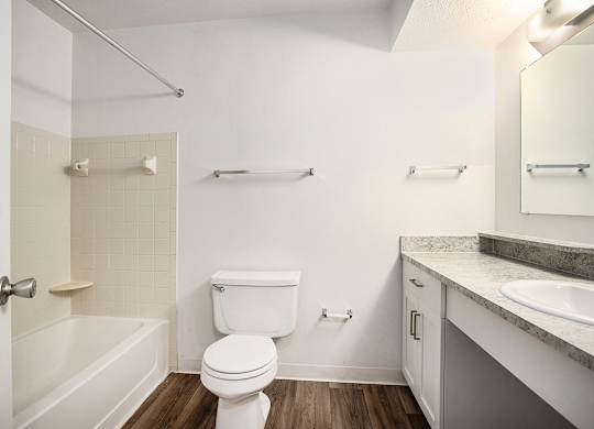 A white bathroom with a toilet, sink, and bathtub at Pine Knoll Apartments, Michigan