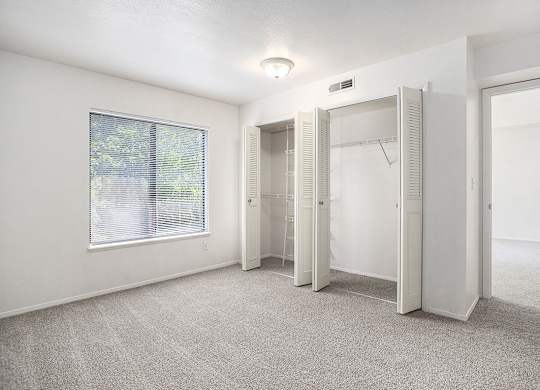 A bedroom with a window and a closet with organizers at Pine Knoll Apartments, Battle Creek, 49014