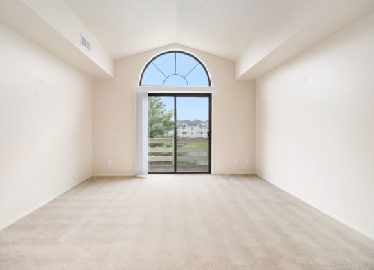 spacious living room with a cathedral ceiling and a slider to a balcony at Pine Knoll Apartments, Battle Creek, MI