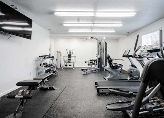 A well-equipped gym with various exercise machines and weights at Polo Run Apartments, Greenwood, Indiana