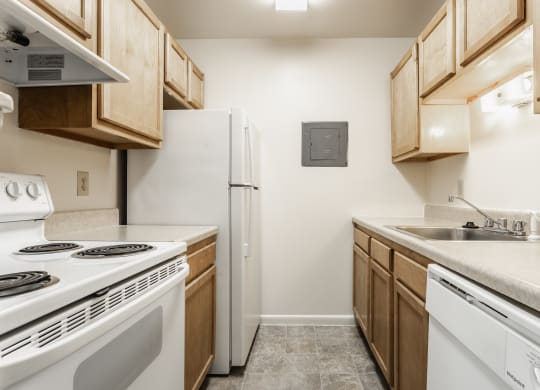 a kitchen with white appliances and wooden cabinets and a white refrigerator at Polo Run Apartments, Greenwood, IN, 46142